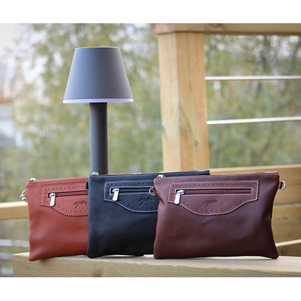 Penelope Emma Handbag: A small, notched handbag with a leather strap and a zippered front pocket, in Brandy, Havana and dark color.