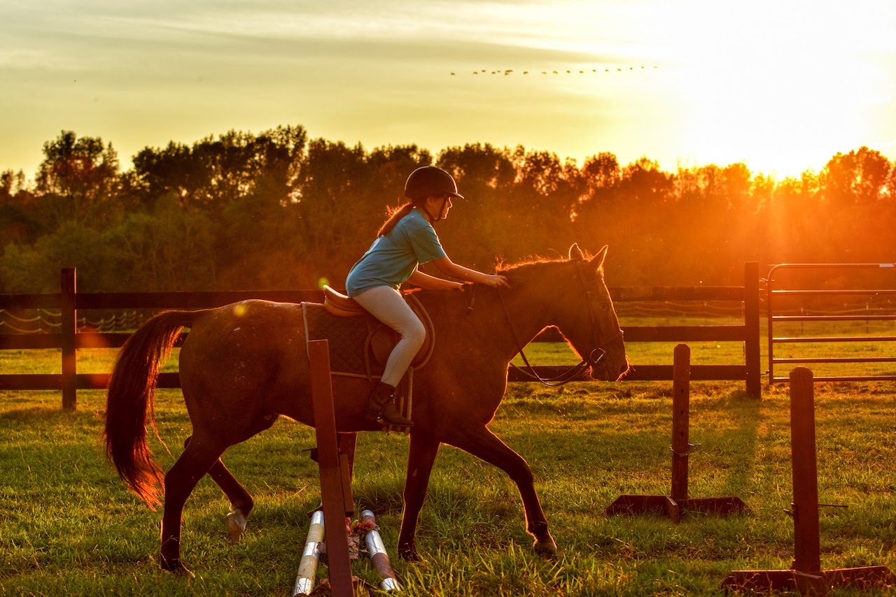 girl riding horse with sunset in background