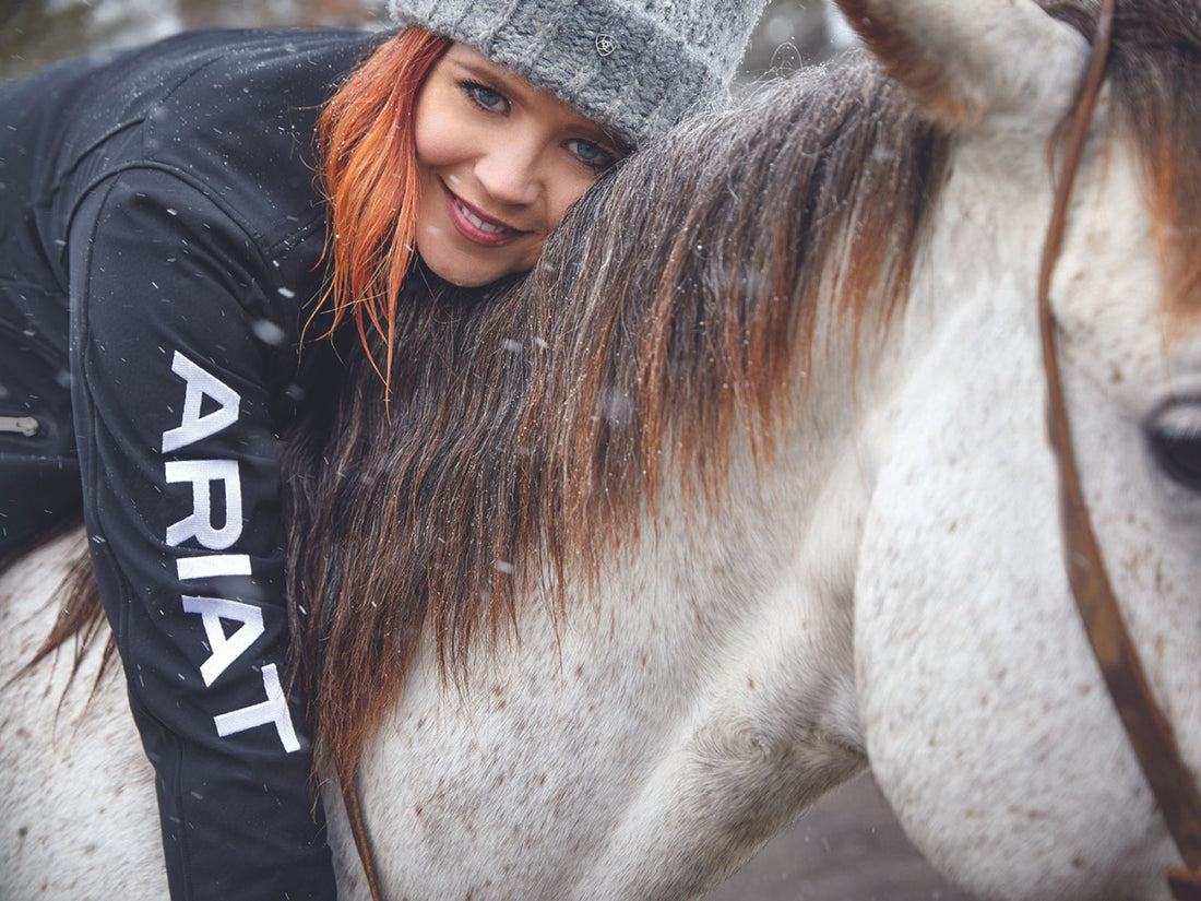 woman hugging horse's neck wearing an Ariat jacket