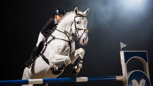 Show jumper wearing KEP helmet on a white horse