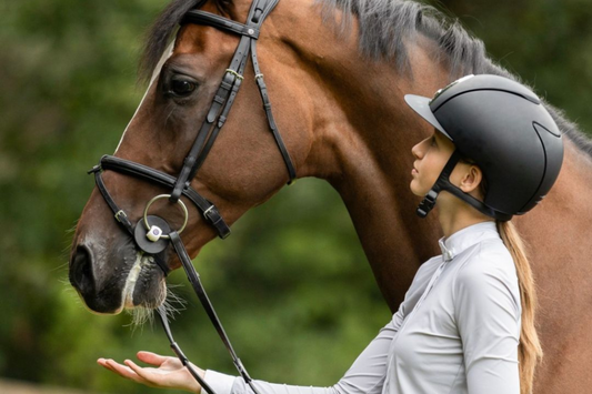 Female rider looks at chestnut horse fitted with Trust bit and bridle