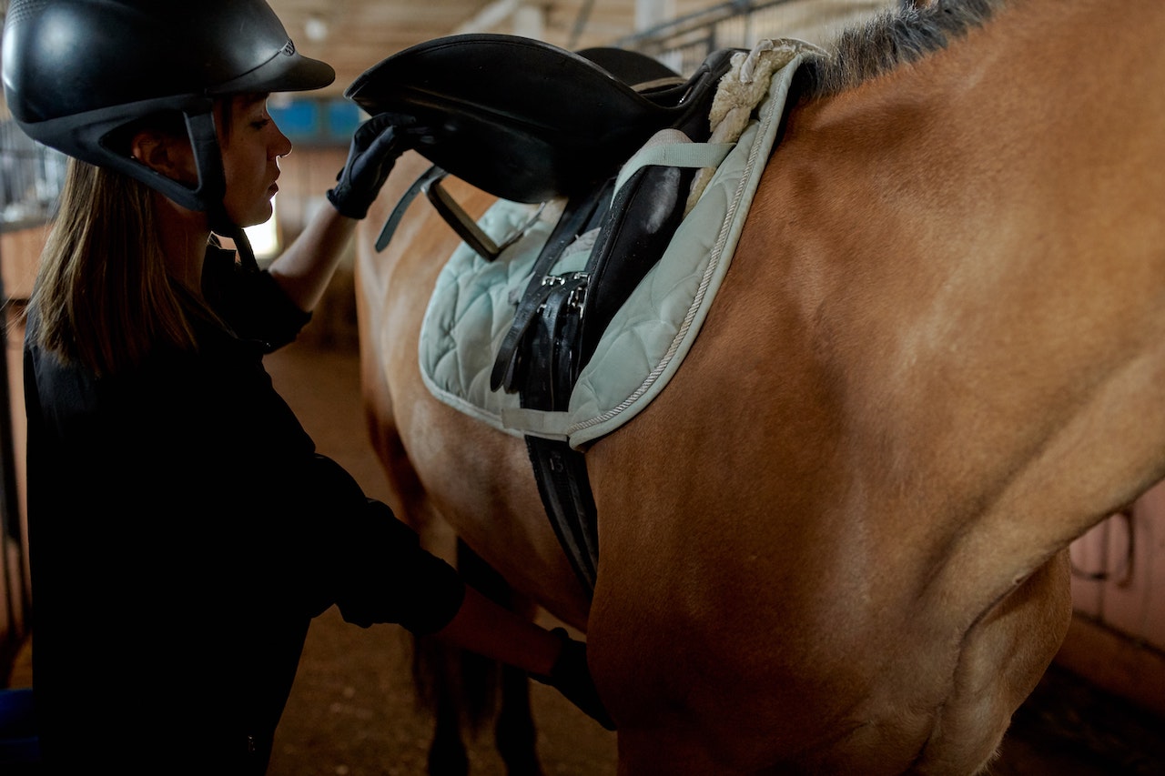 Female rider adjusting saddle pad